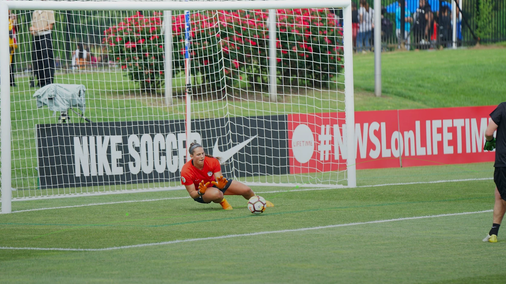 A goalkeeper makes a low save during a competitive adult football match
