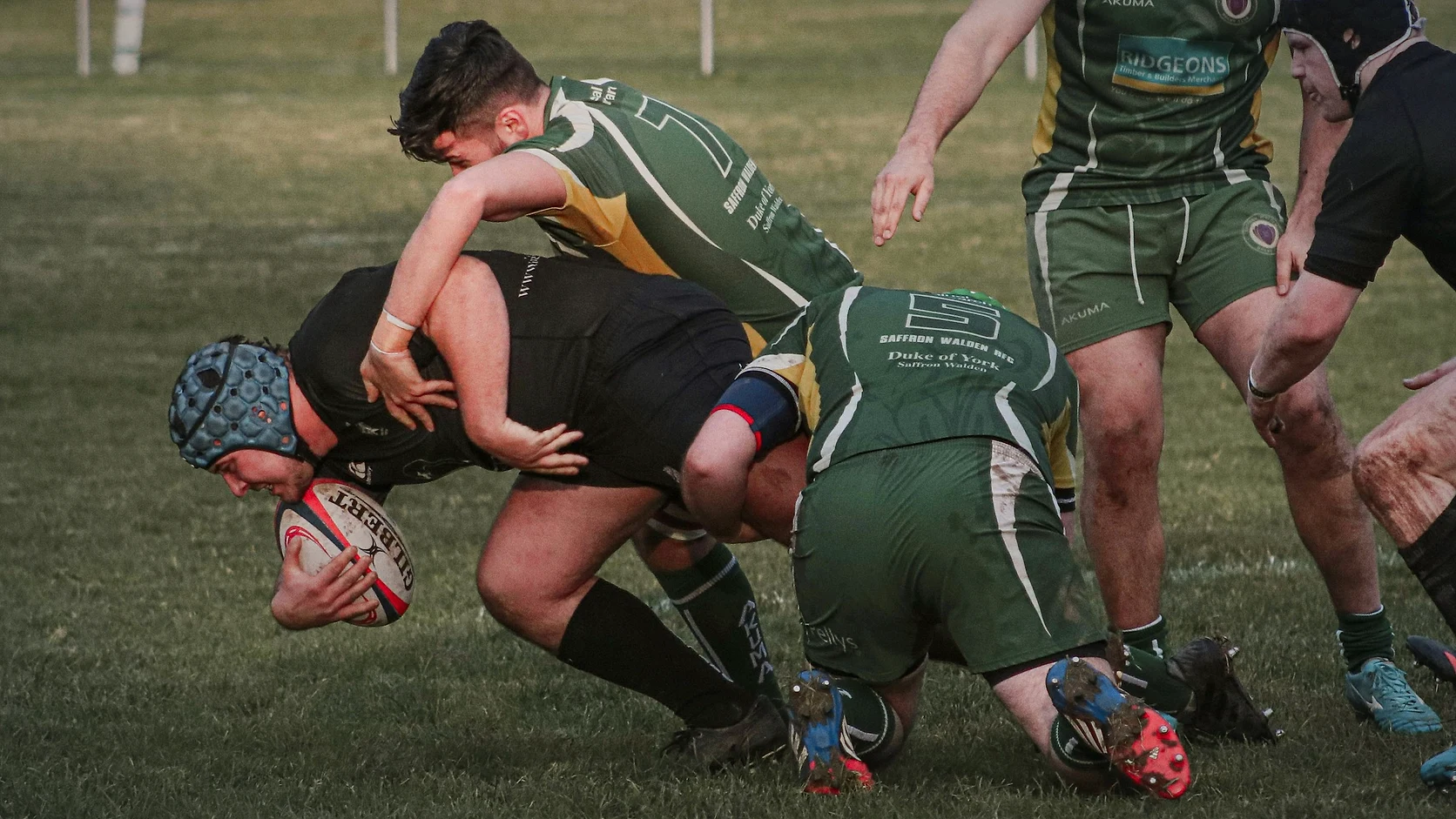 A rugby ball carrier being stopped in a tackle during a club match