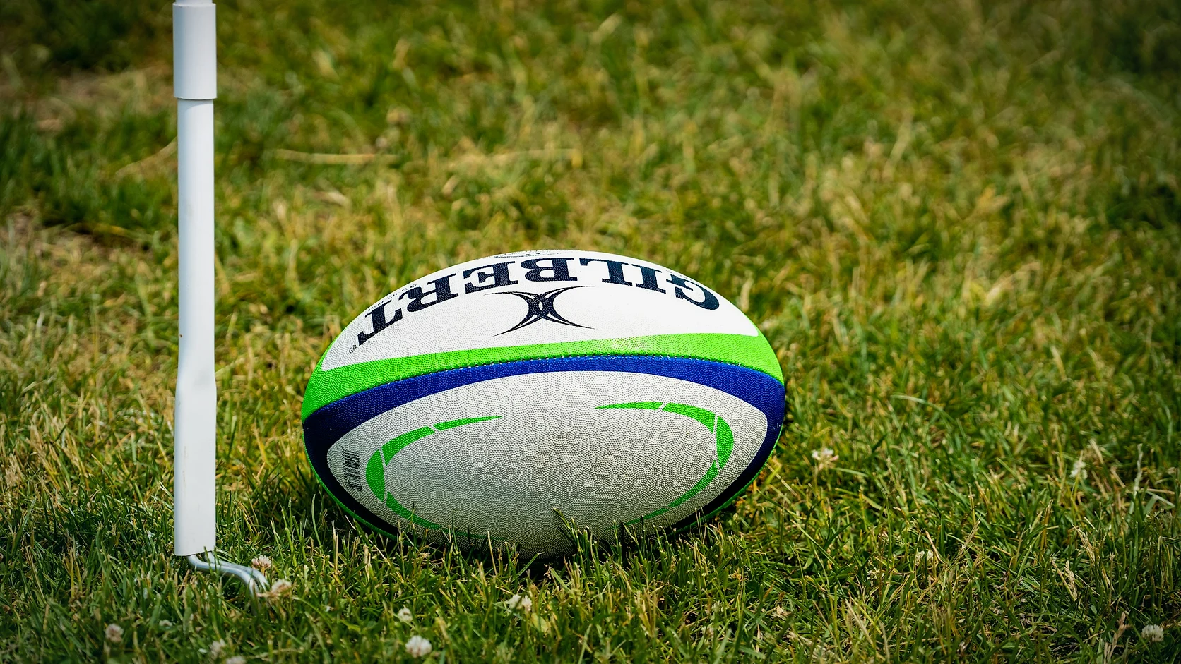 A rugby ball resting beside the corner flag and touchline