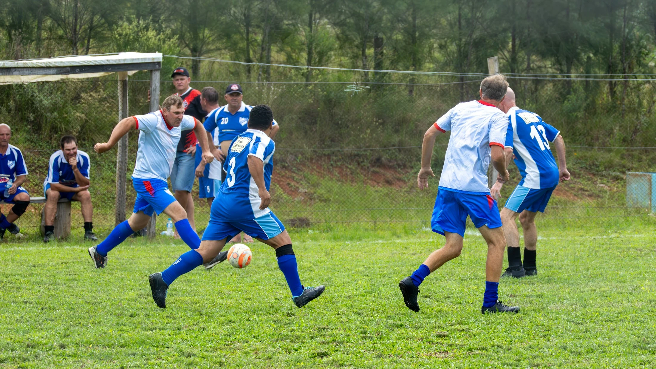 Adult footballers competing on a grass pitch